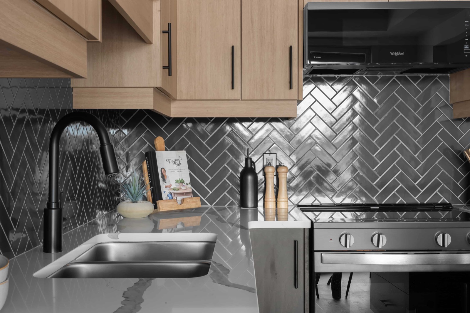 Kitchen detail with matte black faucet and herringbone backsplash in a decorated model home