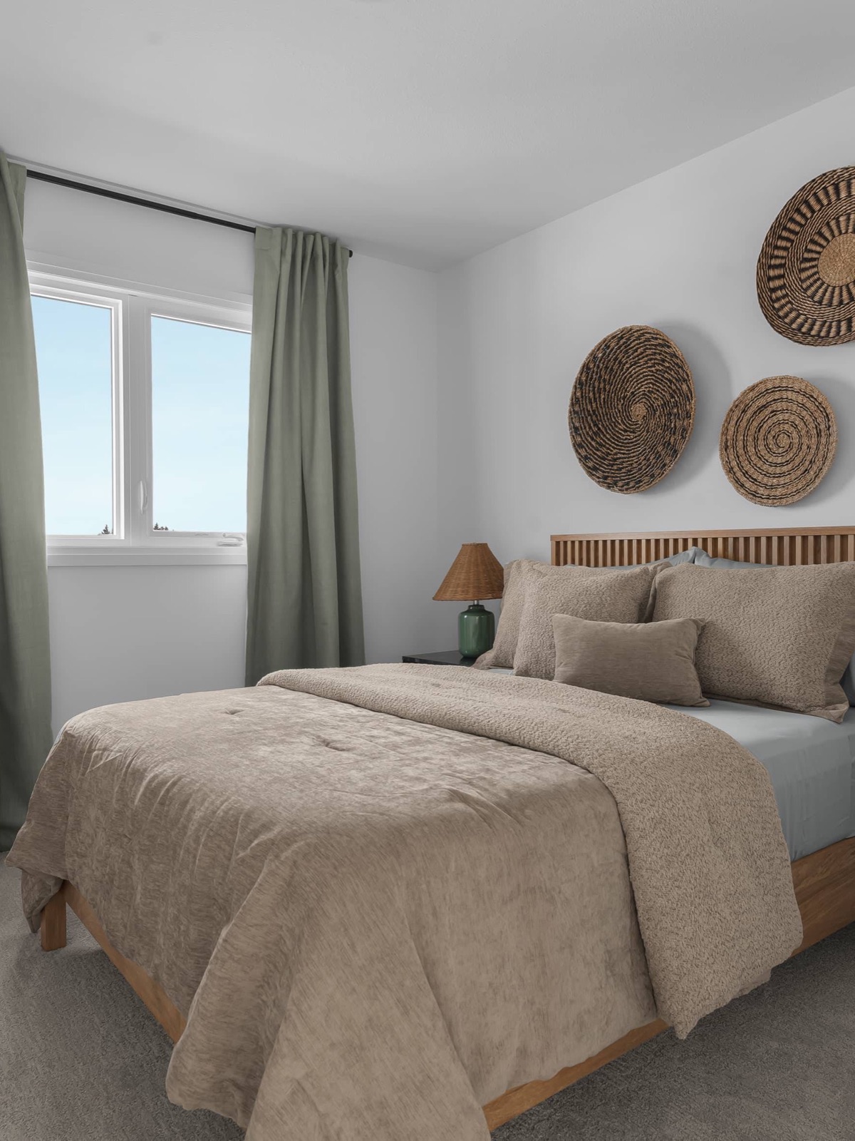 Bedroom with oak slat headboard and sage drapery in a decorated model home