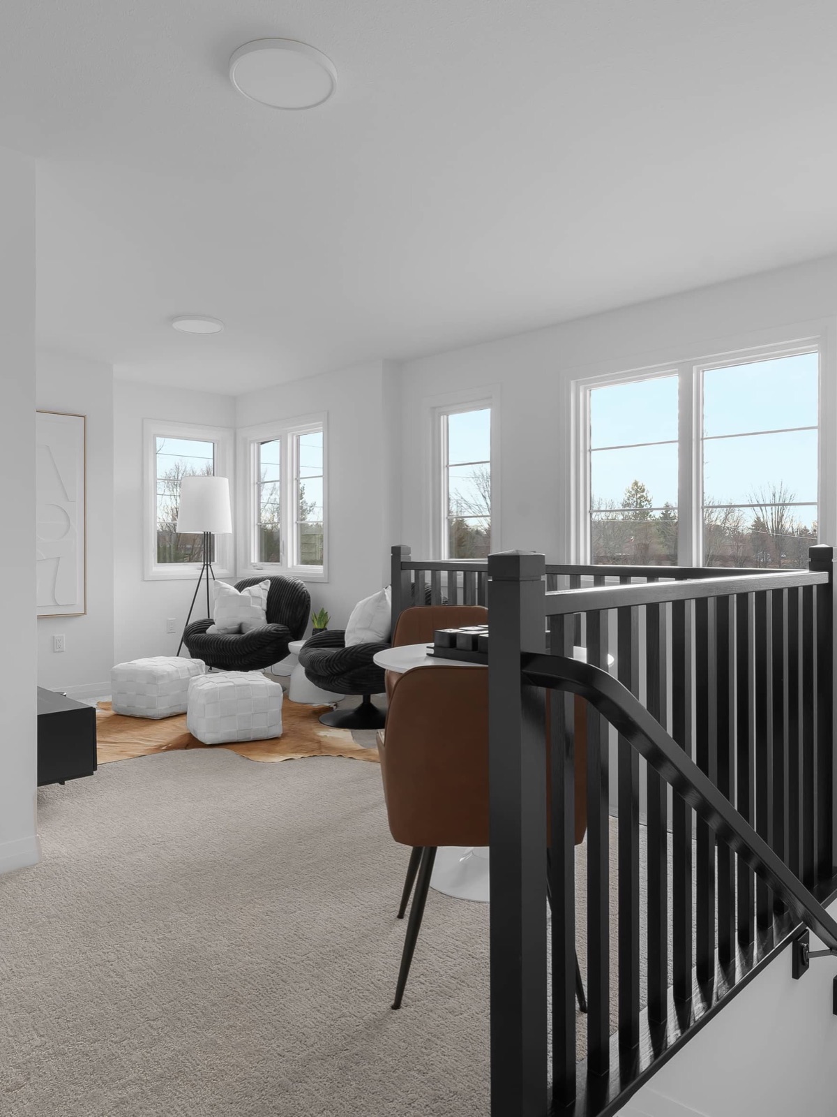 Bright upstairs loft lounge with black spindle railing in a decorated model home